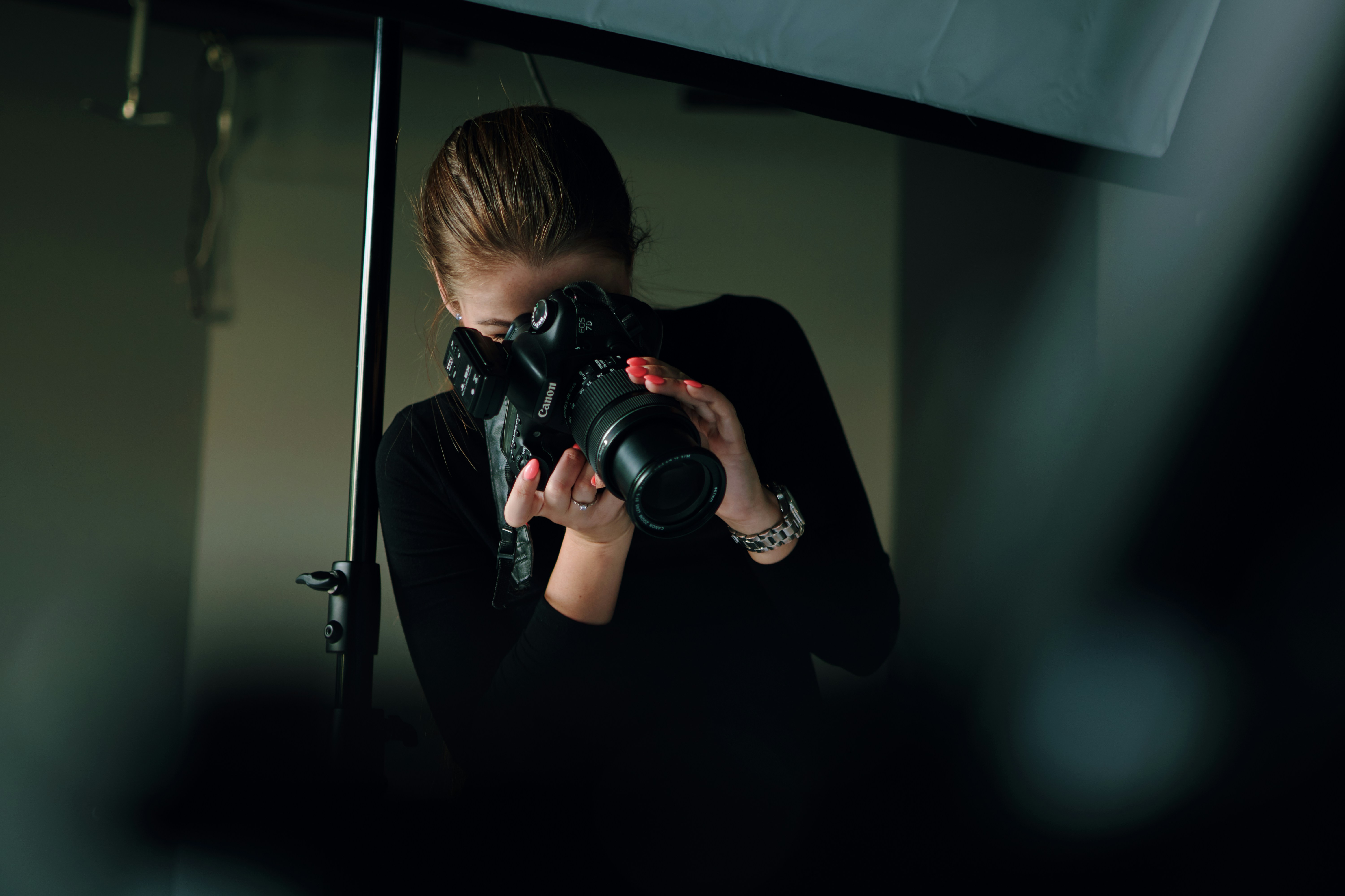 Photographer dressed in black shooting with a DSLR camera in a studio with a softbox. The first steps in how to build a photography portfolio.
